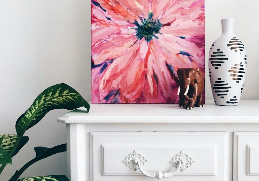 painting of pink flower on dresser near white vase