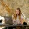 A woman sitting on a bench using a laptop computer