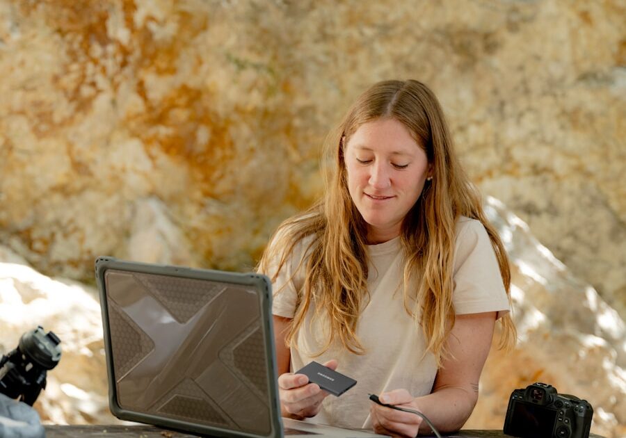 A woman sitting on a bench using a laptop computer