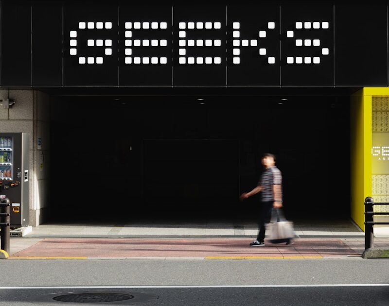 A man walking down a street next to a tall building