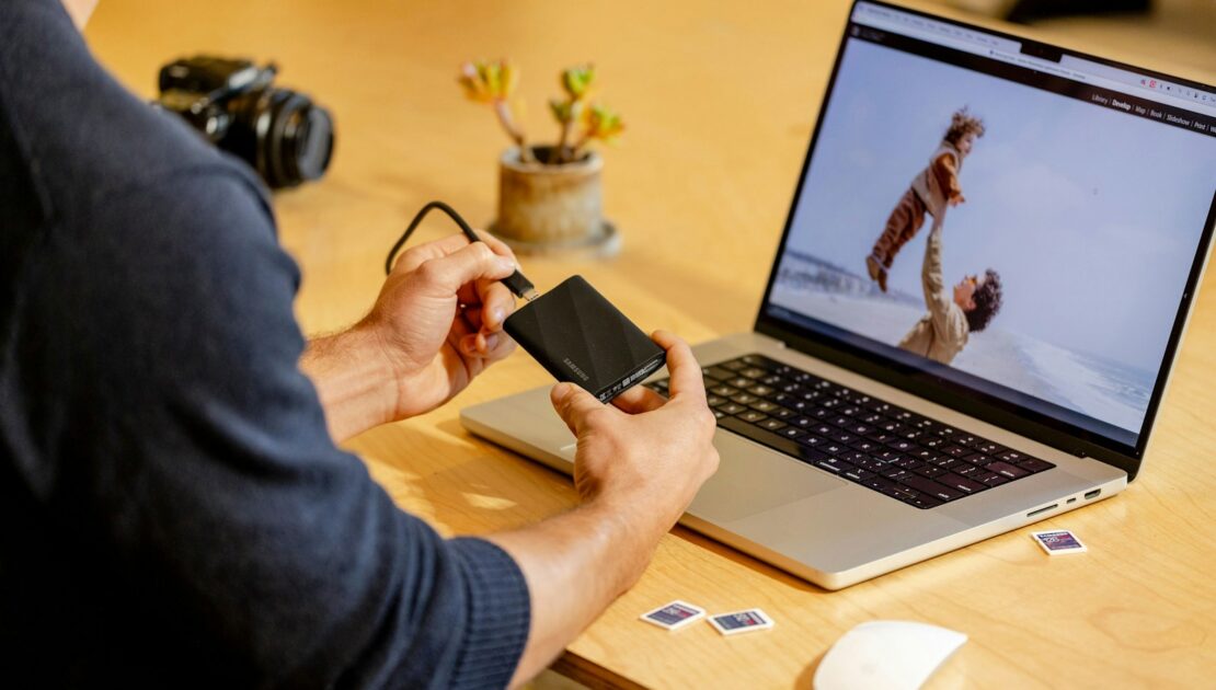 A man sitting at a table with a laptop and cell phone